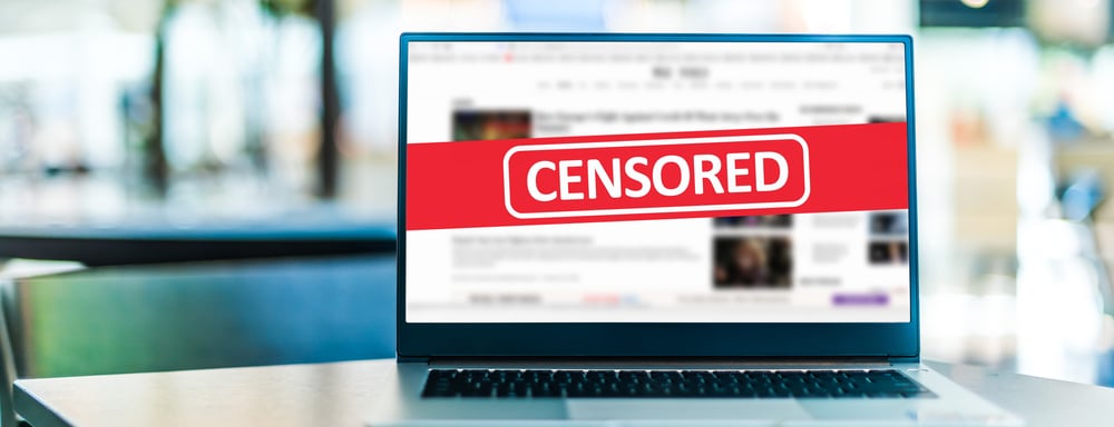 Bærbar computer tilsluttet internettet med rød censureret etiket på skærmen.